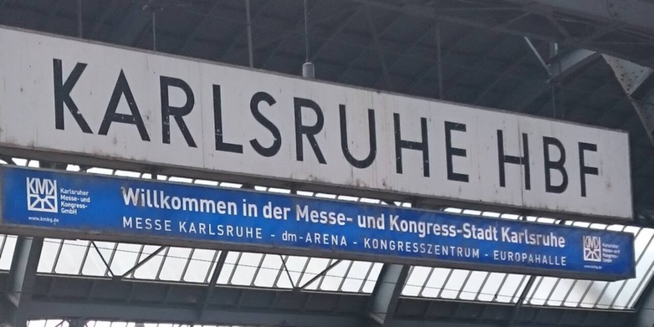 A photo of a large suspended Karlsruhe Hauptbahnhof sign